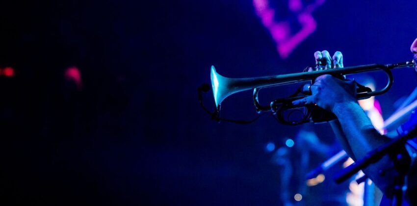 Close-up van een trompettist onder blauw en paars podiumlicht