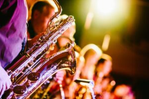 Close-up van een saxofoon bij een verlicht blazersensemble op het podium